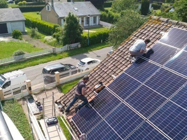 Deux hommes sur une toiture en train d'installer des panneaux solaires