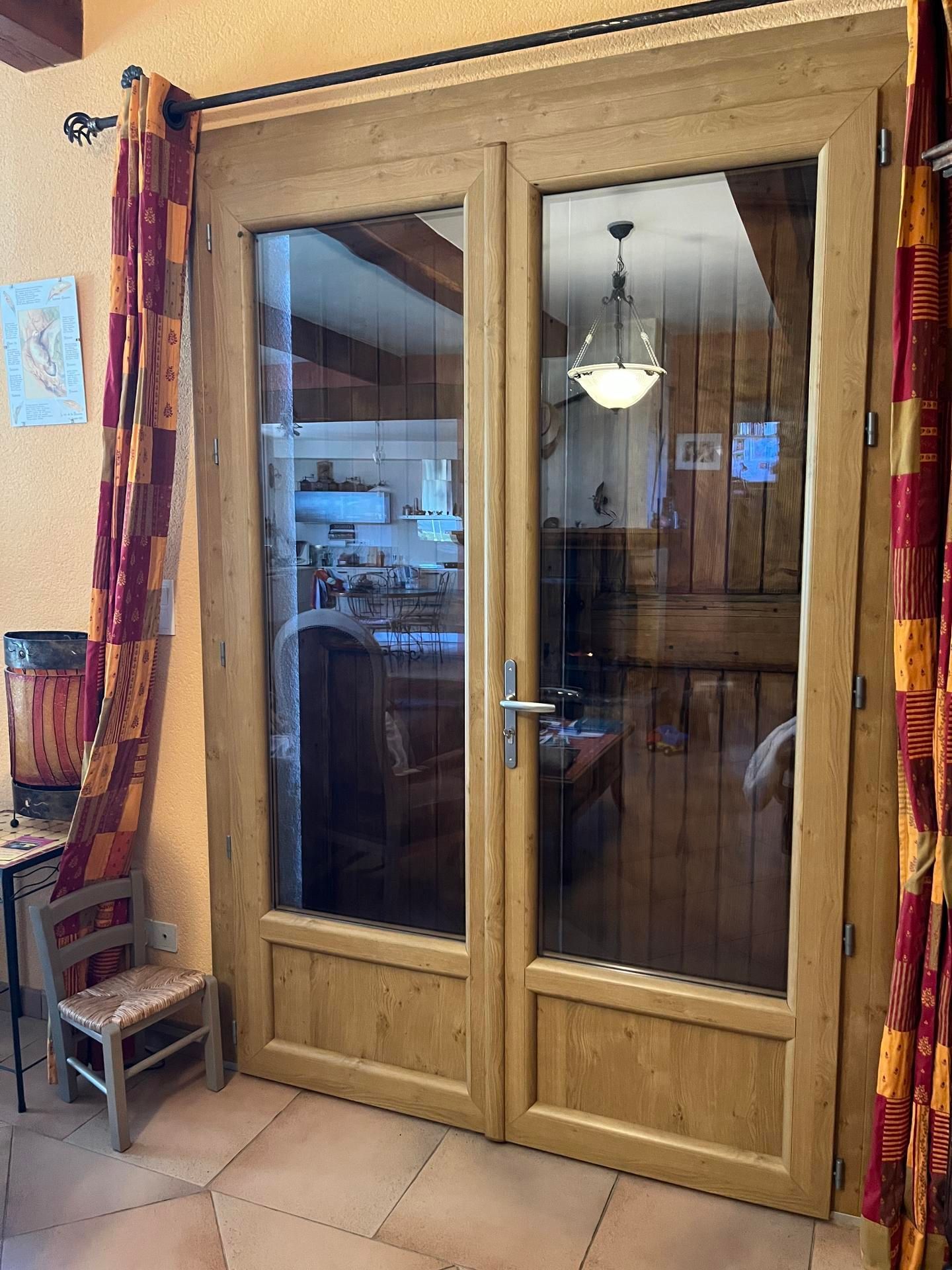Des portes doubles en bois et vitrées avec des rideaux à motifs.