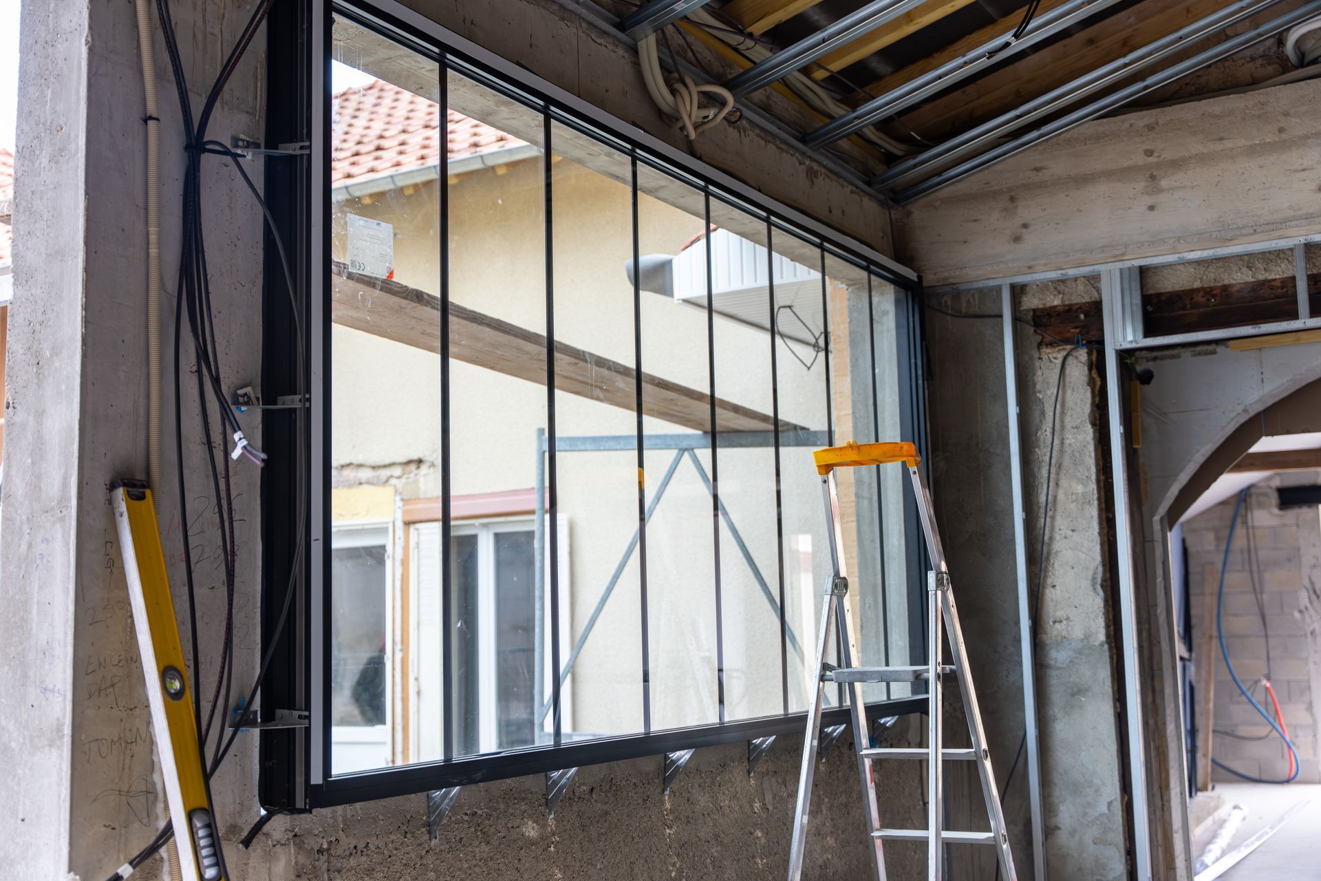 Une fenêtre à cadre noir avec des croisillons verticaux, installée dans une pièce inachevée.