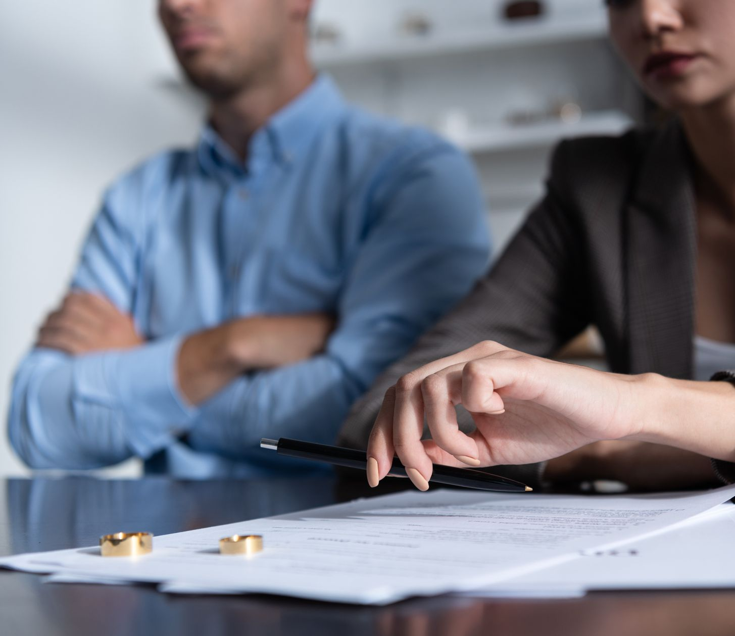 Deux personnes sont assises à une table avec des papiers de divorce et des alliances