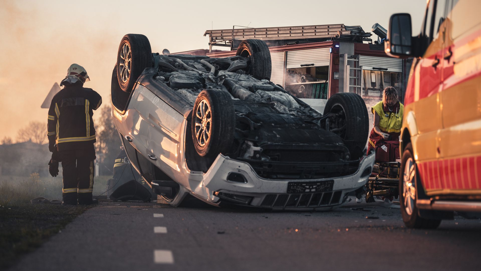Les secours sont sur les lieux d'un accident de voiture, où un véhicule blanc s'est renversé sur la route.