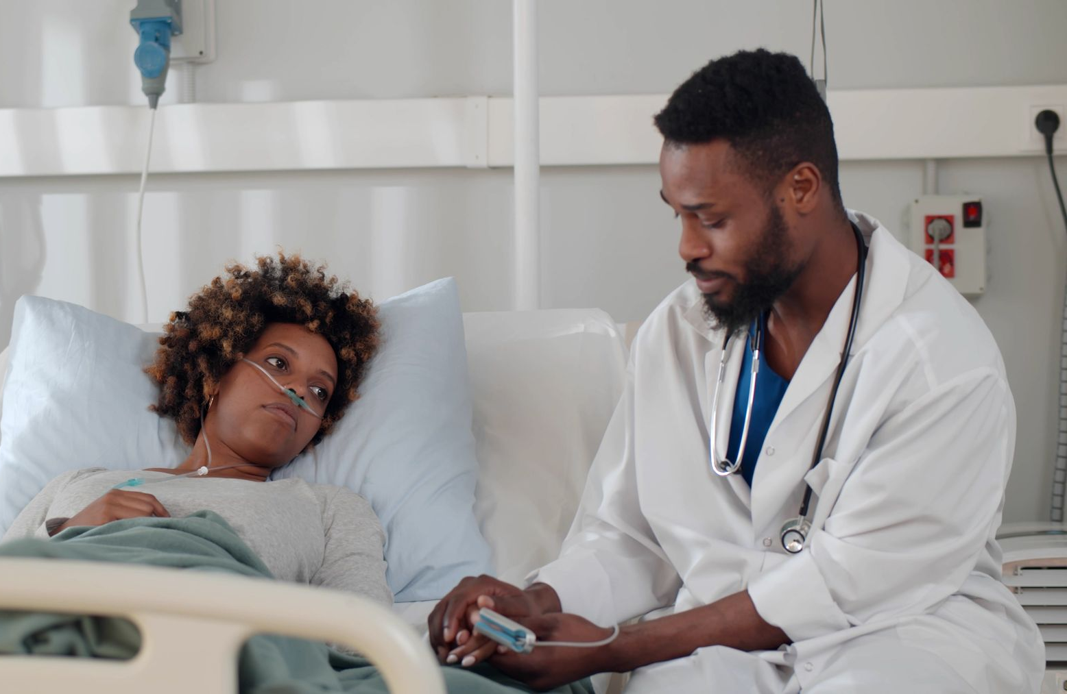 Un professionnel de santé est assis au chevet d'un patient hospitalisé