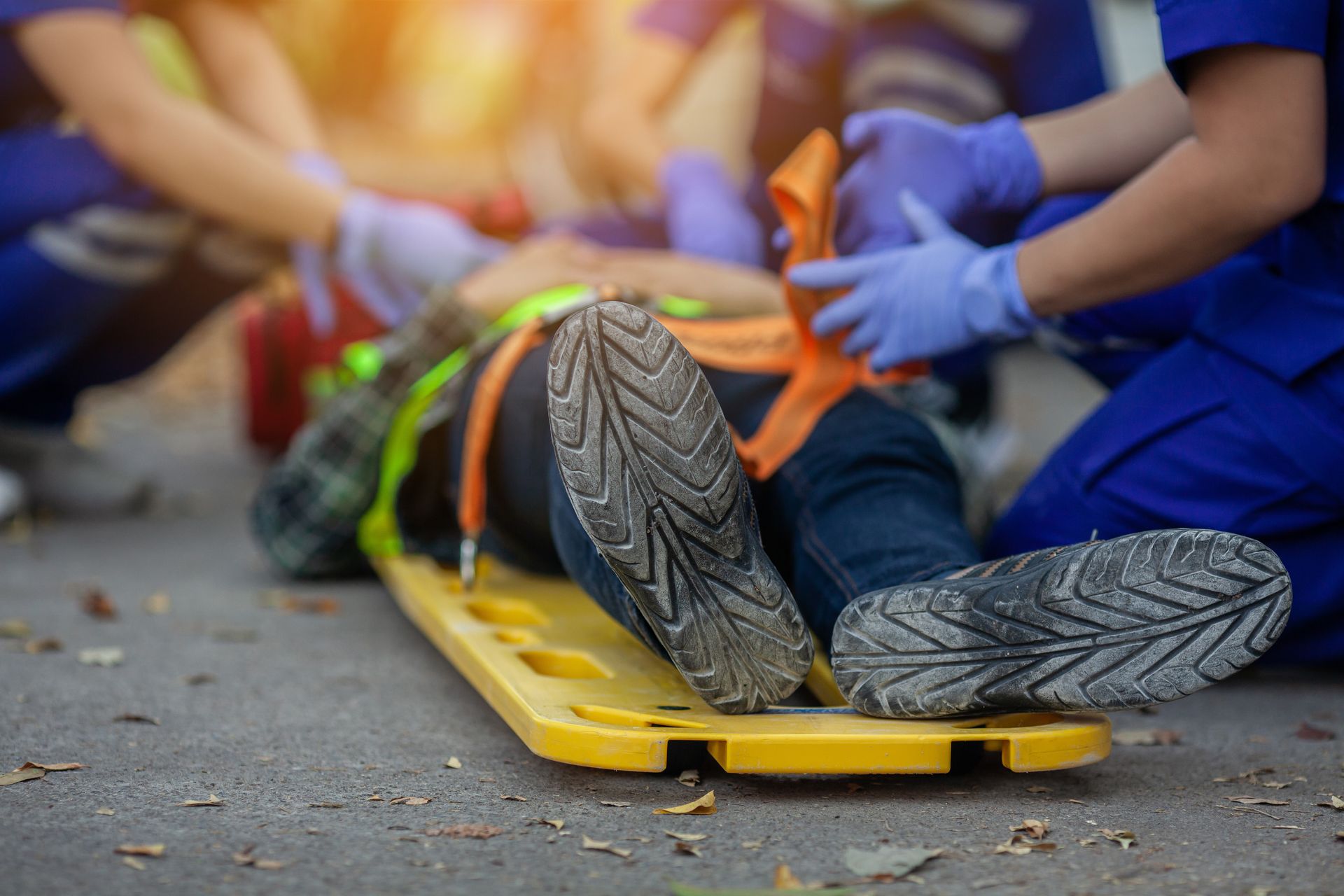 Des secouristes vêtus d'uniformes et de gants bleus immobilisent une personne sur une planche dorsale jaune