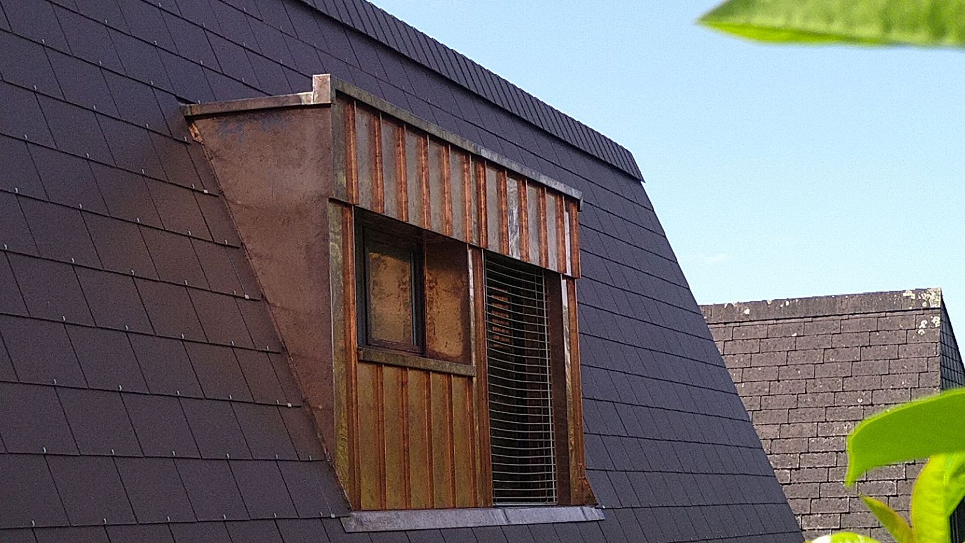 Ein Fenster an der Seite eines Gebäudes mit Schieferdach