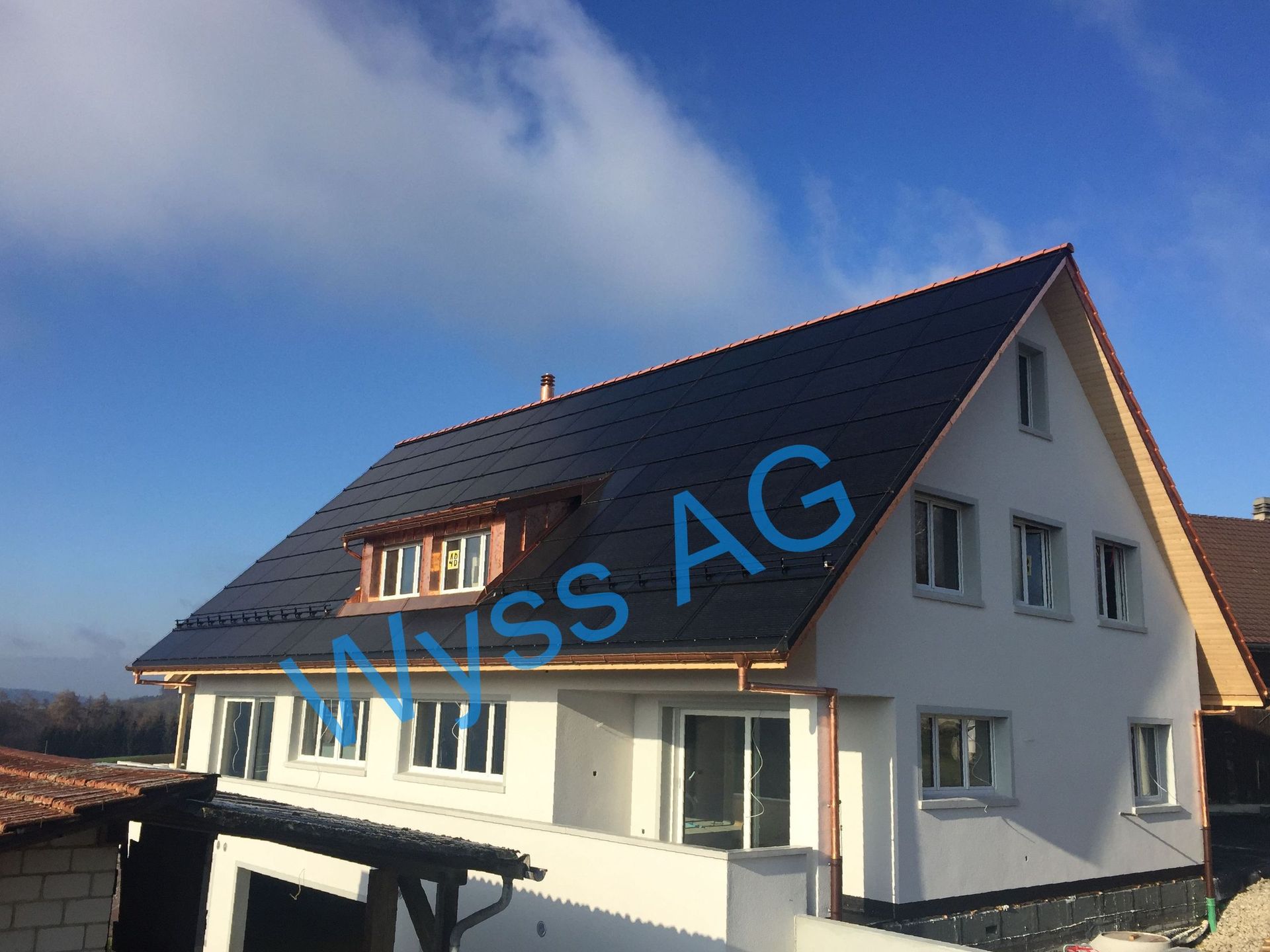 Ein weißes Haus mit einem schwarzen Dach und dem Wort „ag“ darauf