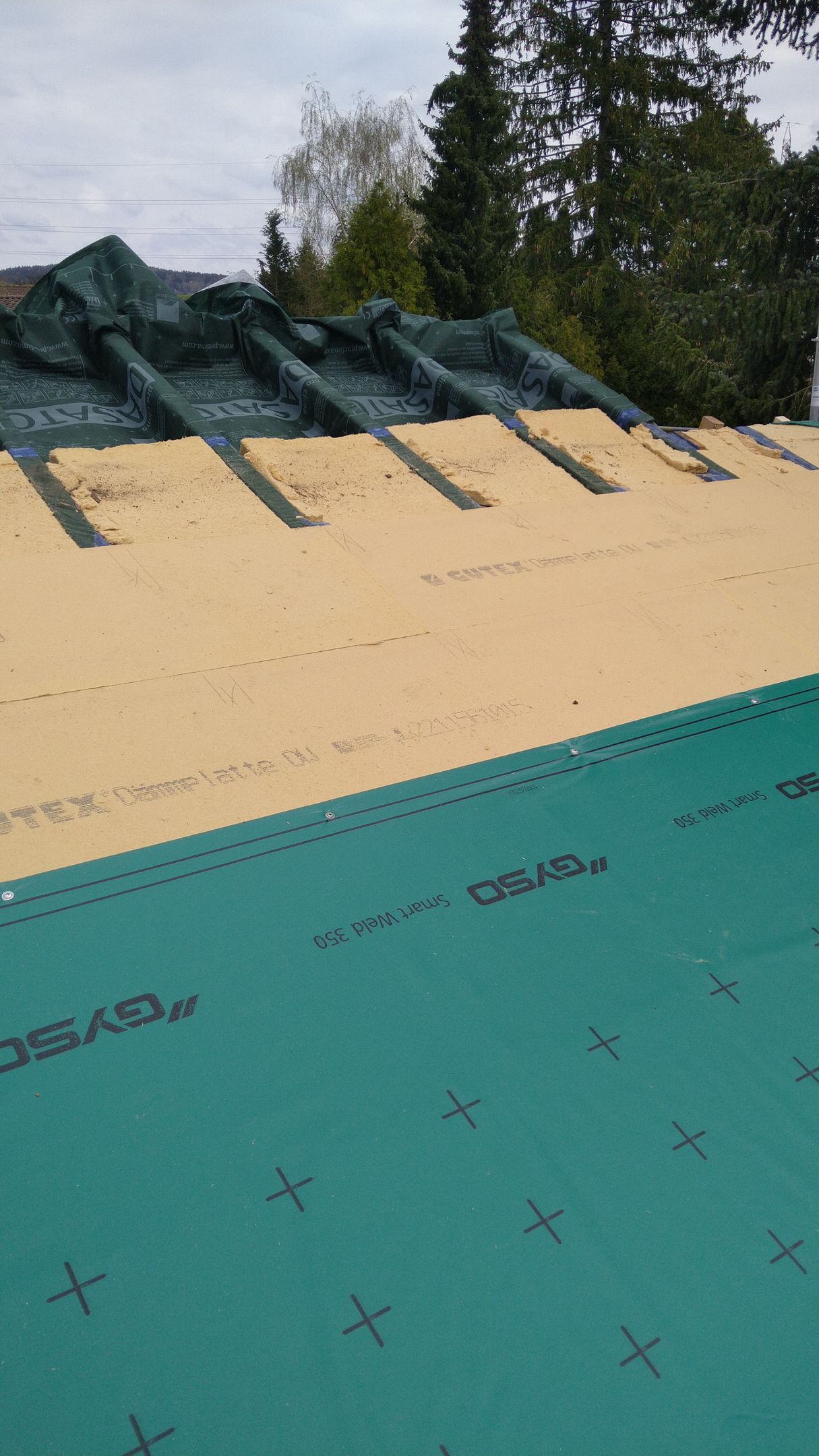 Ein Dach wird mit einer grünen Plane abgedeckt.