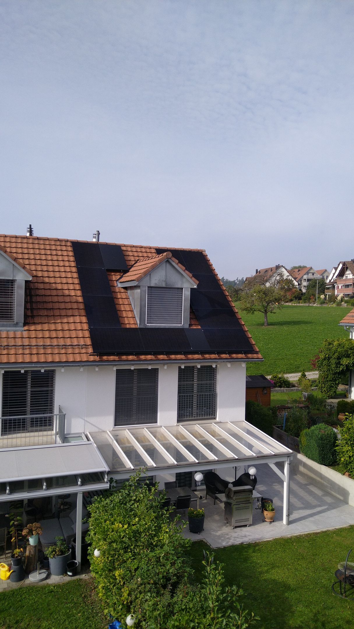 Ein Haus mit Pergola und Sonnenkollektoren auf dem Dach.