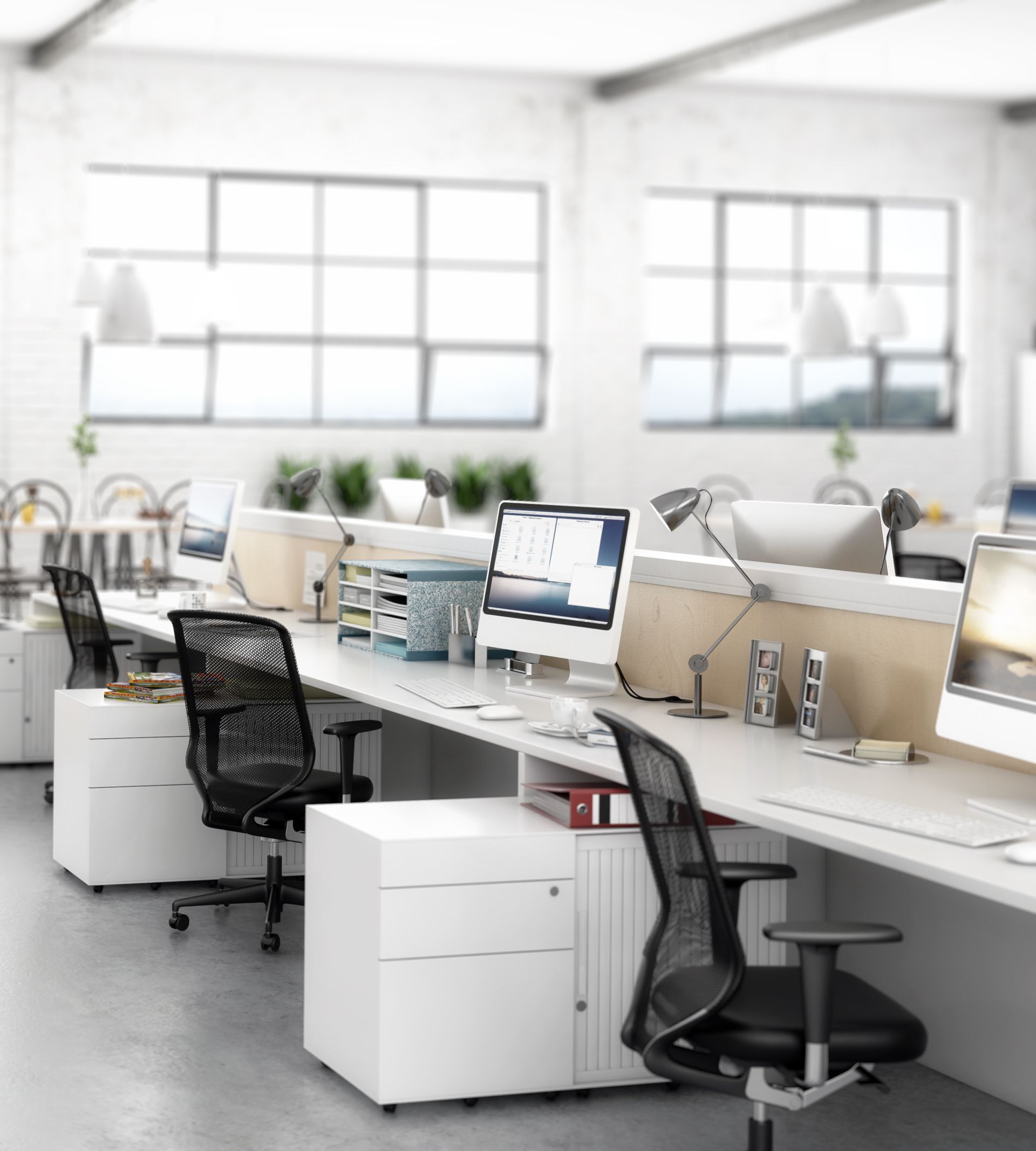 Intérieur de bureau avec bureaux blancs, ordinateurs, chaises noires et grandes fenêtres.