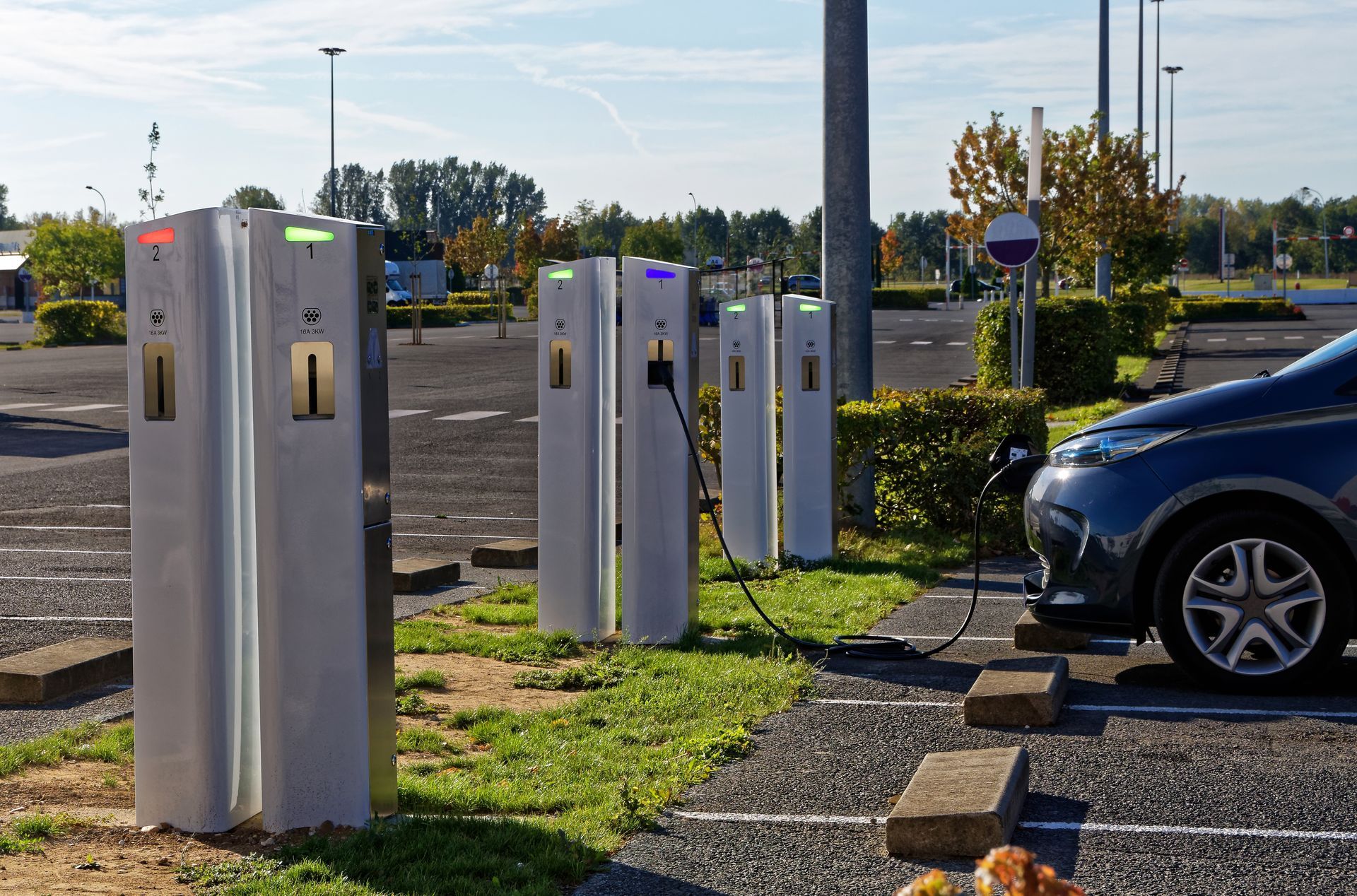 Voiture électrique en charge à une borne. Bornes de recharge argentées avec éclairage multicolore. La voiture est bleu foncé.