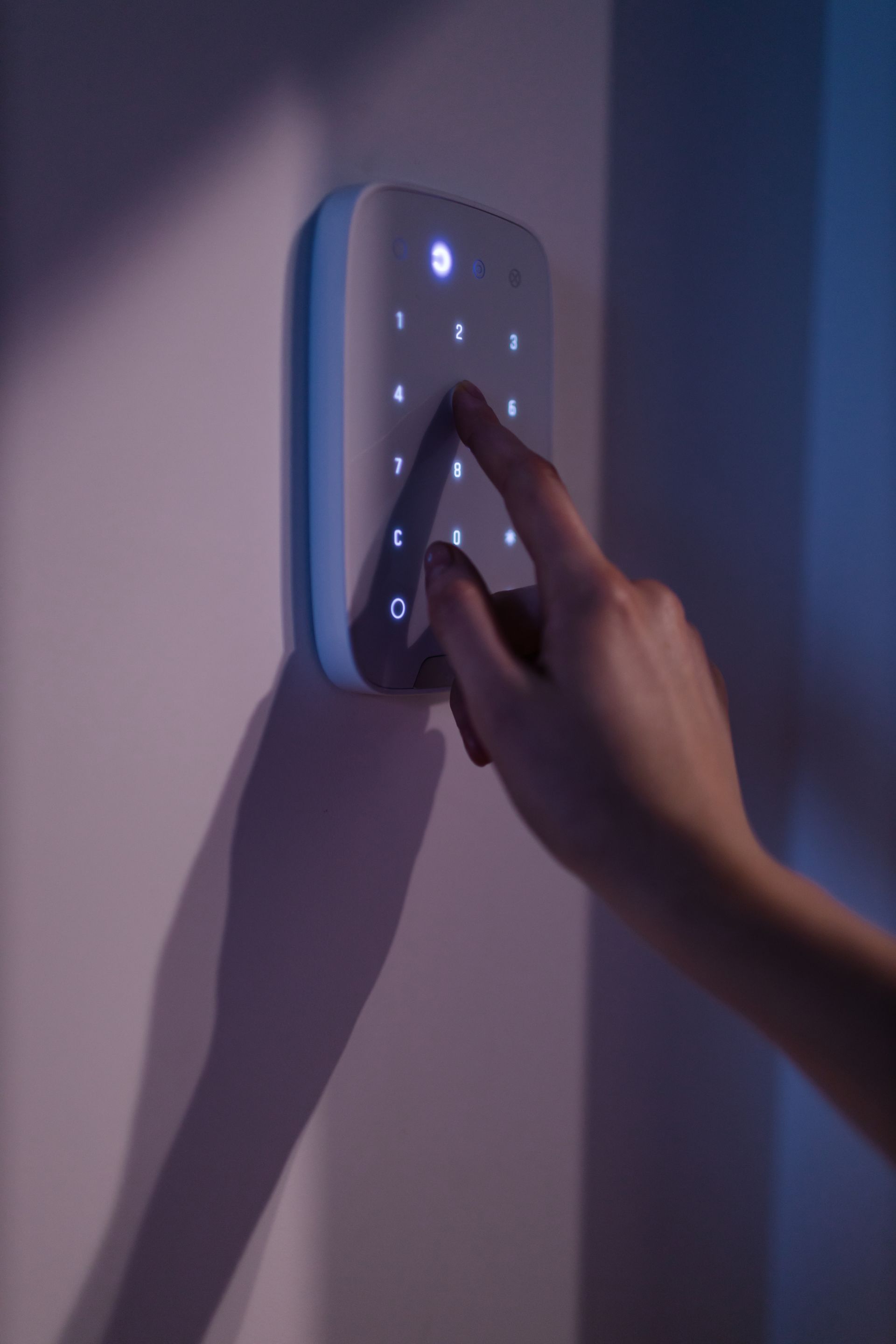 Saisie manuelle d'un code sur un clavier blanc fixé au mur.