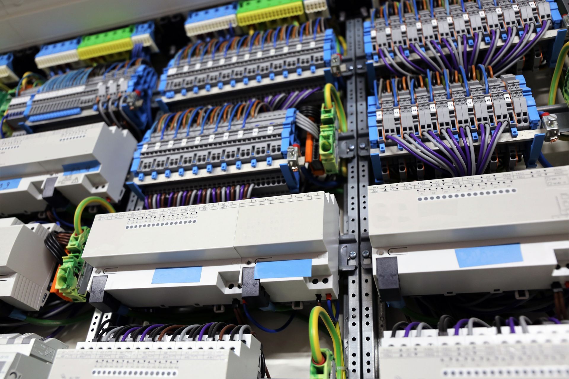 Gros plan sur le câblage électrique d'un panneau de commande, avec des fils de différentes couleurs et des borniers.