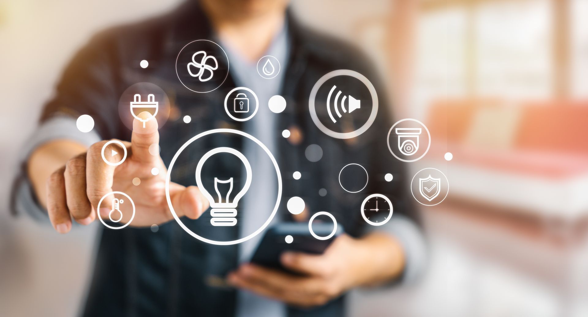 Une personne interagit avec un smartphone et sélectionne une icône d'ampoule parmi les commandes de la maison connectée.