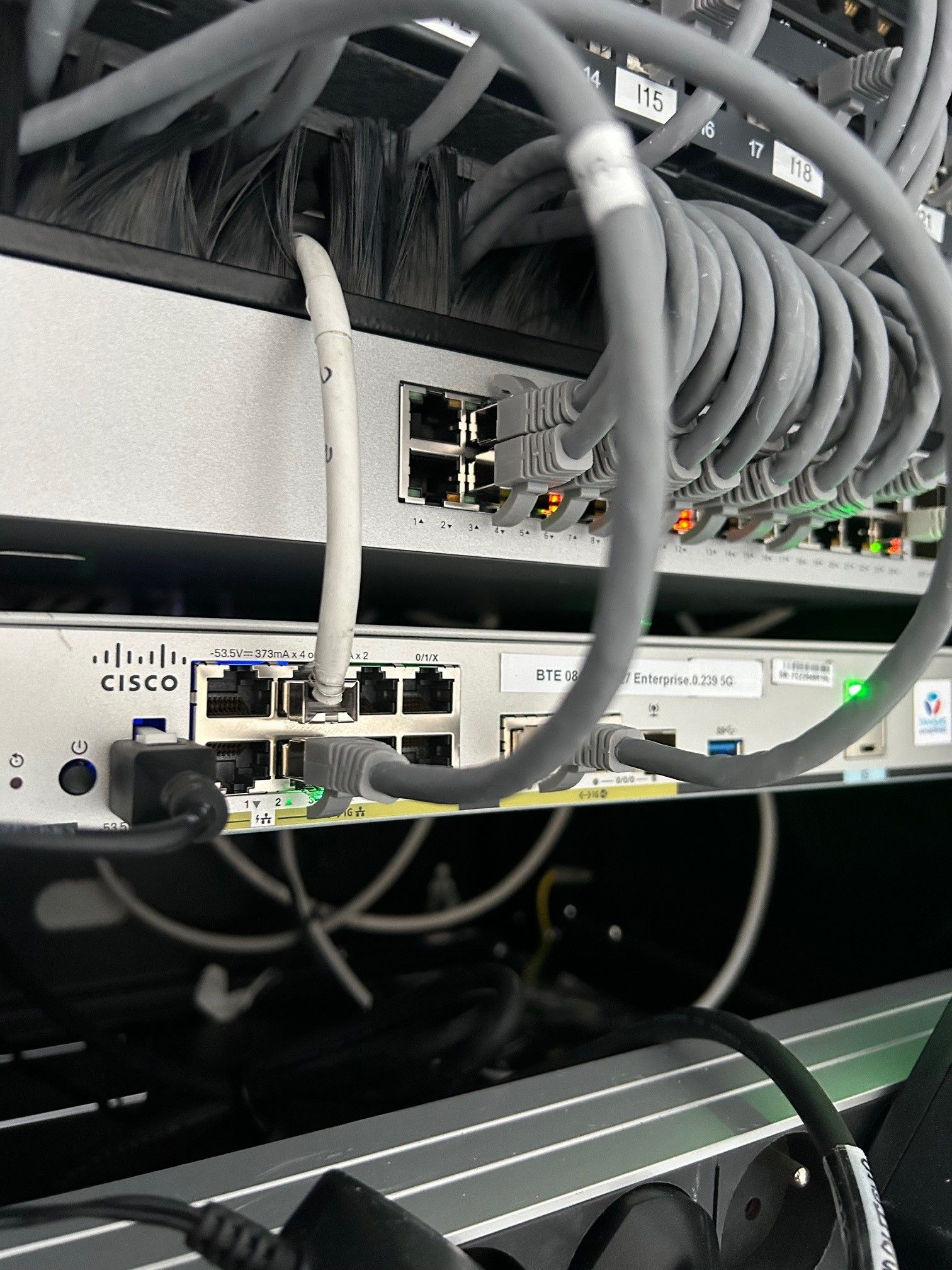 Serveurs réseau avec un enchevêtrement de câbles gris connectés à différents ports.