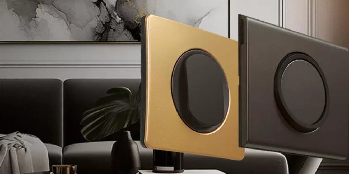 Gros plan sur des plaques d'interrupteurs modernes dorées et noires, avec des boutons noirs, dans un salon.