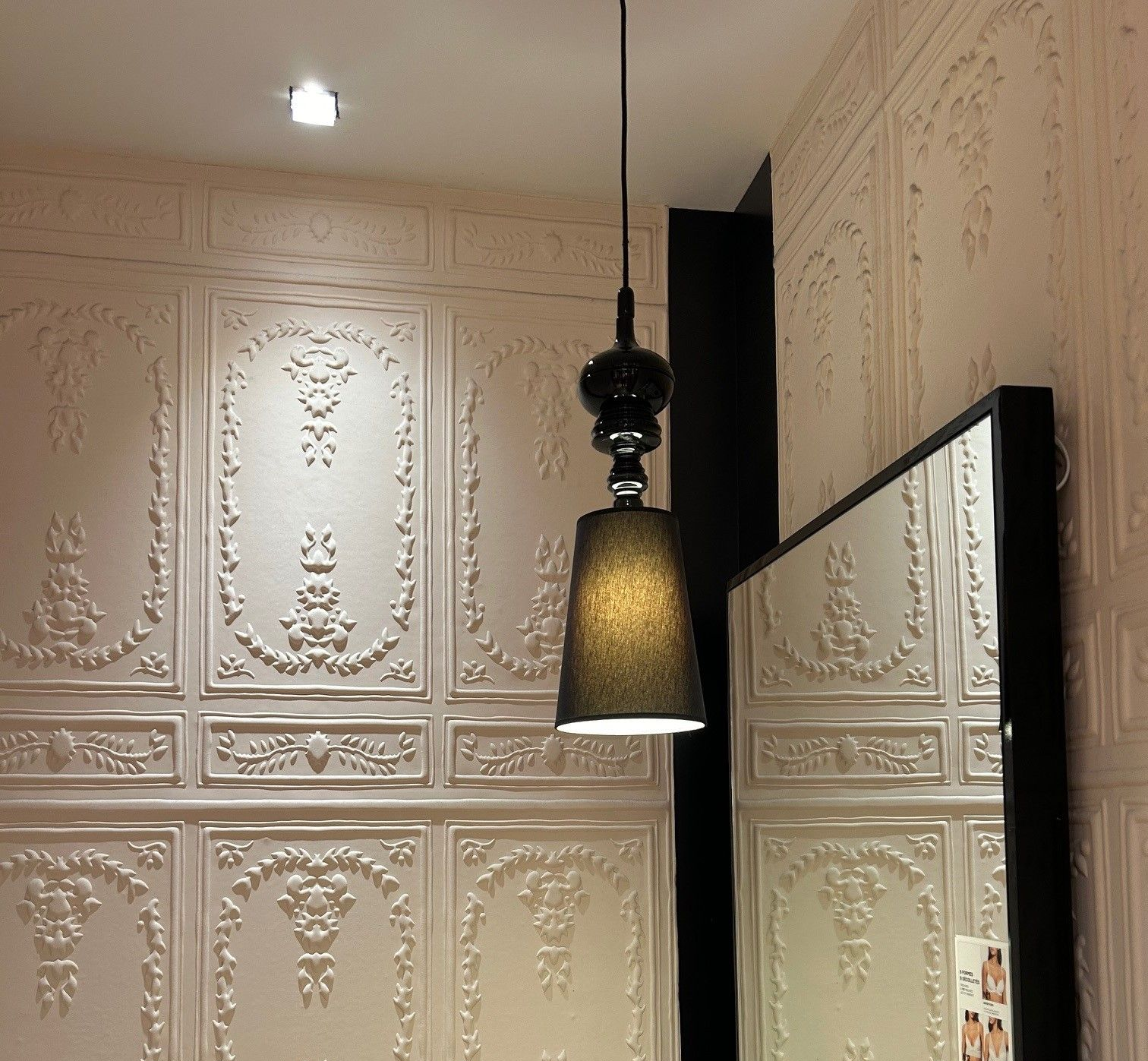 Panneaux muraux blancs ornés, avec une suspension noire et un miroir.