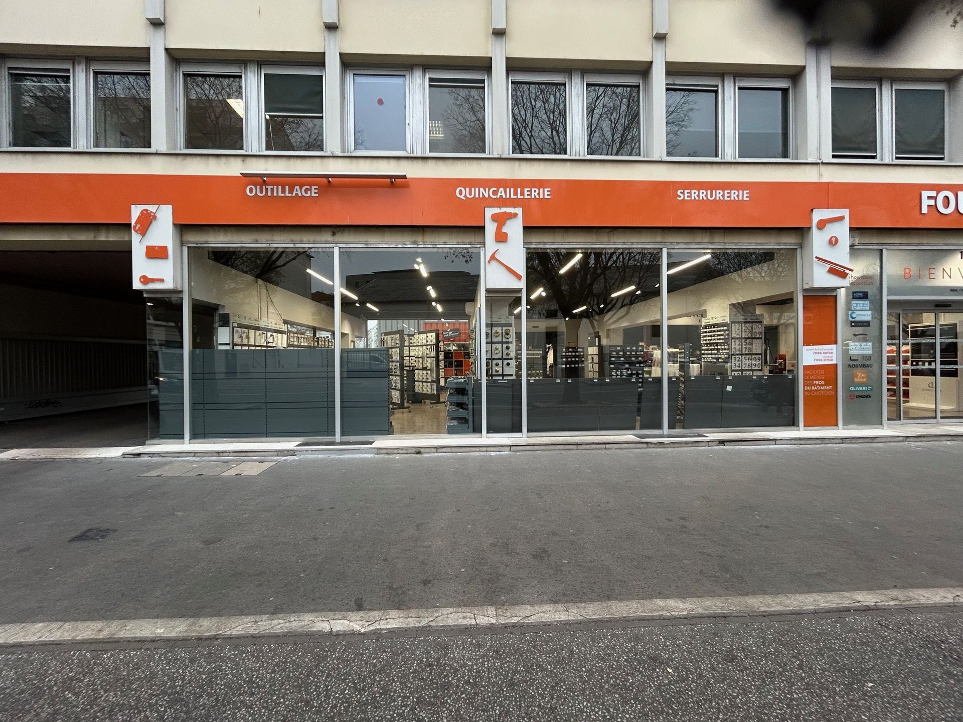 Un magasin avec une enseigne orange et des vitrines exposant des outils et du matériel.