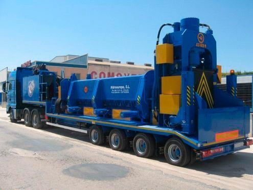 Una gran máquina azul y amarilla está en un remolque