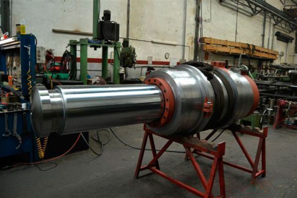 Un gran objeto de metal se encuentra sobre un soporte rojo en una fábrica.