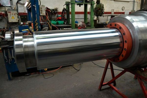 Un gran cilindro de metal se encuentra sobre un soporte rojo en una fábrica.