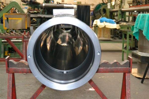 Un tubo de metal está sobre un soporte de madera en una fábrica.