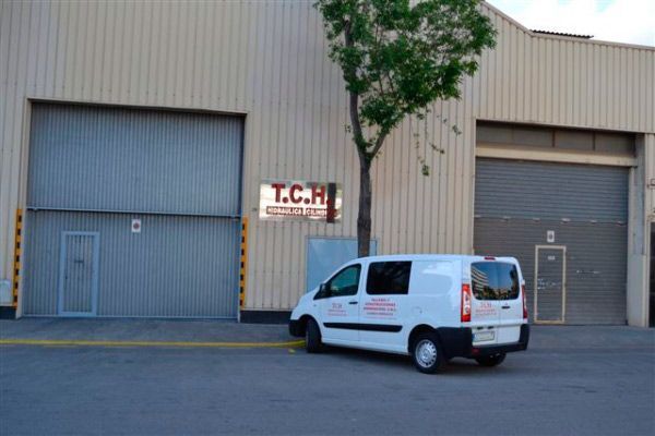 Una camioneta blanca está estacionada frente a un edificio que dice tcri