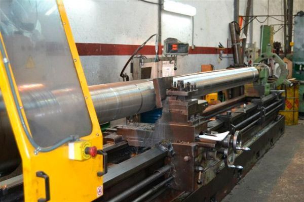 Un gran torno amarillo se encuentra en una fábrica.