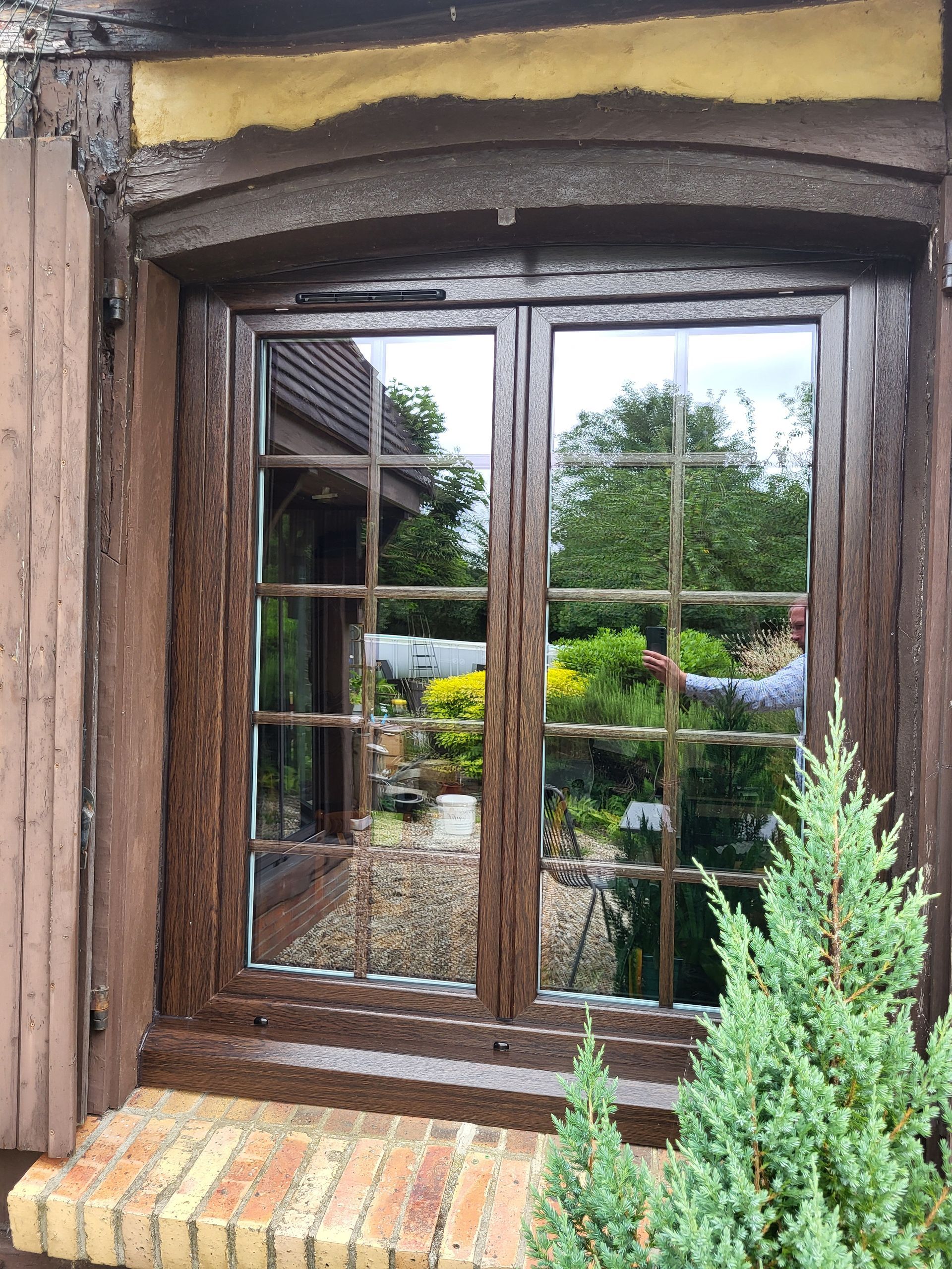 Reflet d'un homme prenant la photo à travers la vitre extérieure d'une porte-fenêtre.