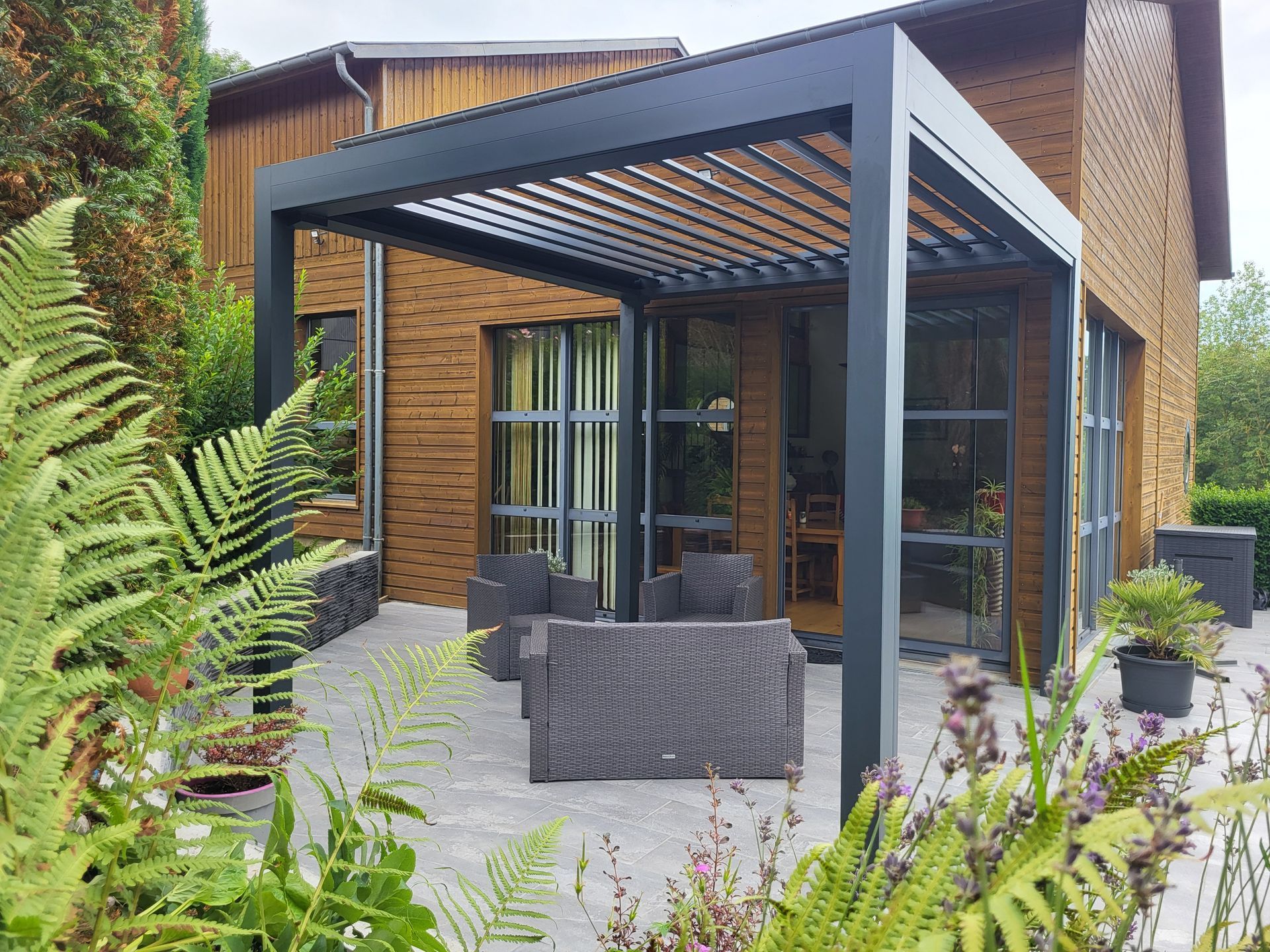 Sièges sous une pergola sur la terrasse d'une maison.