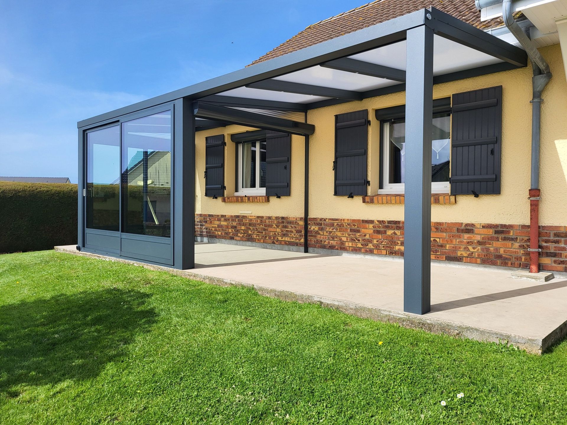 Pergolas avec baies vitrées contre la façade d'une habitation.