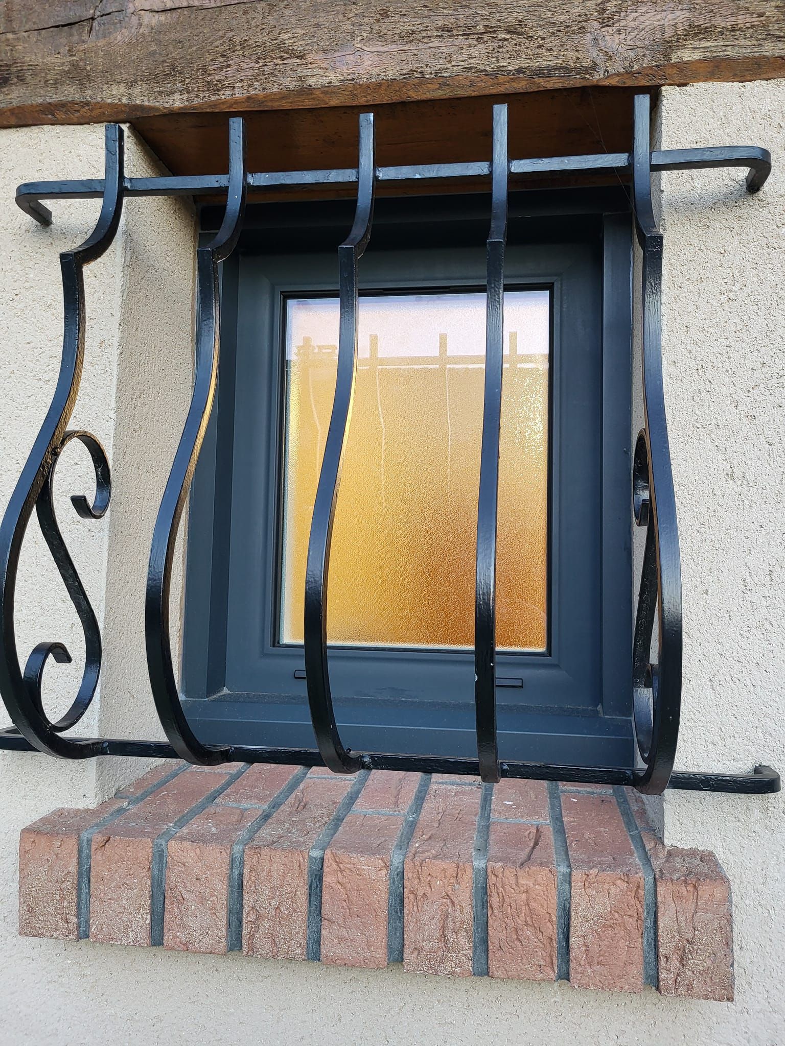 Petite fenêtre protégée par du fer forgé.