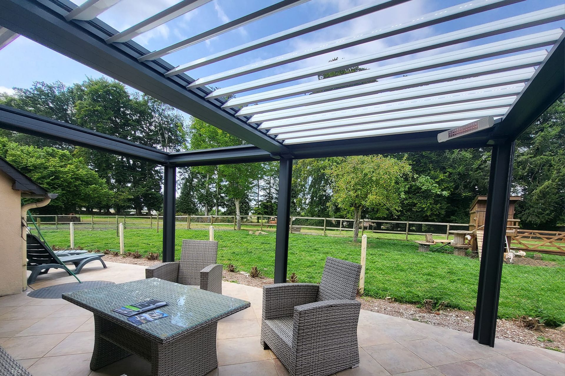 Vue du jardin sur une terrasse sous une pergola.