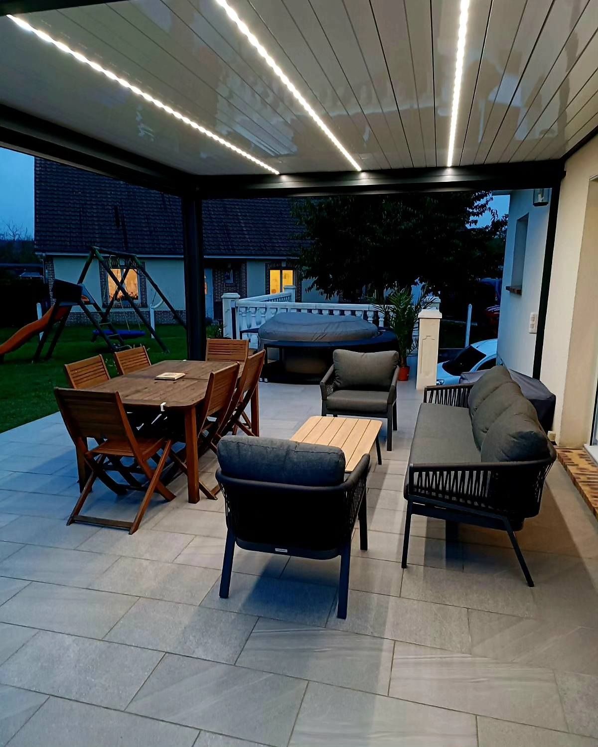 Table chaises et sièges sous une pergola au début de la nuit.