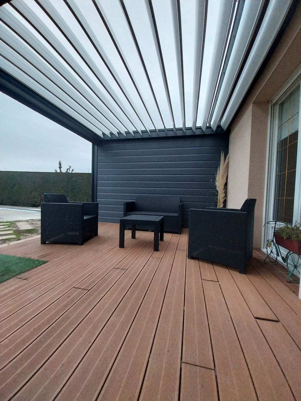 Table basse et sièges sur une terrasse en bois sous une pergola.