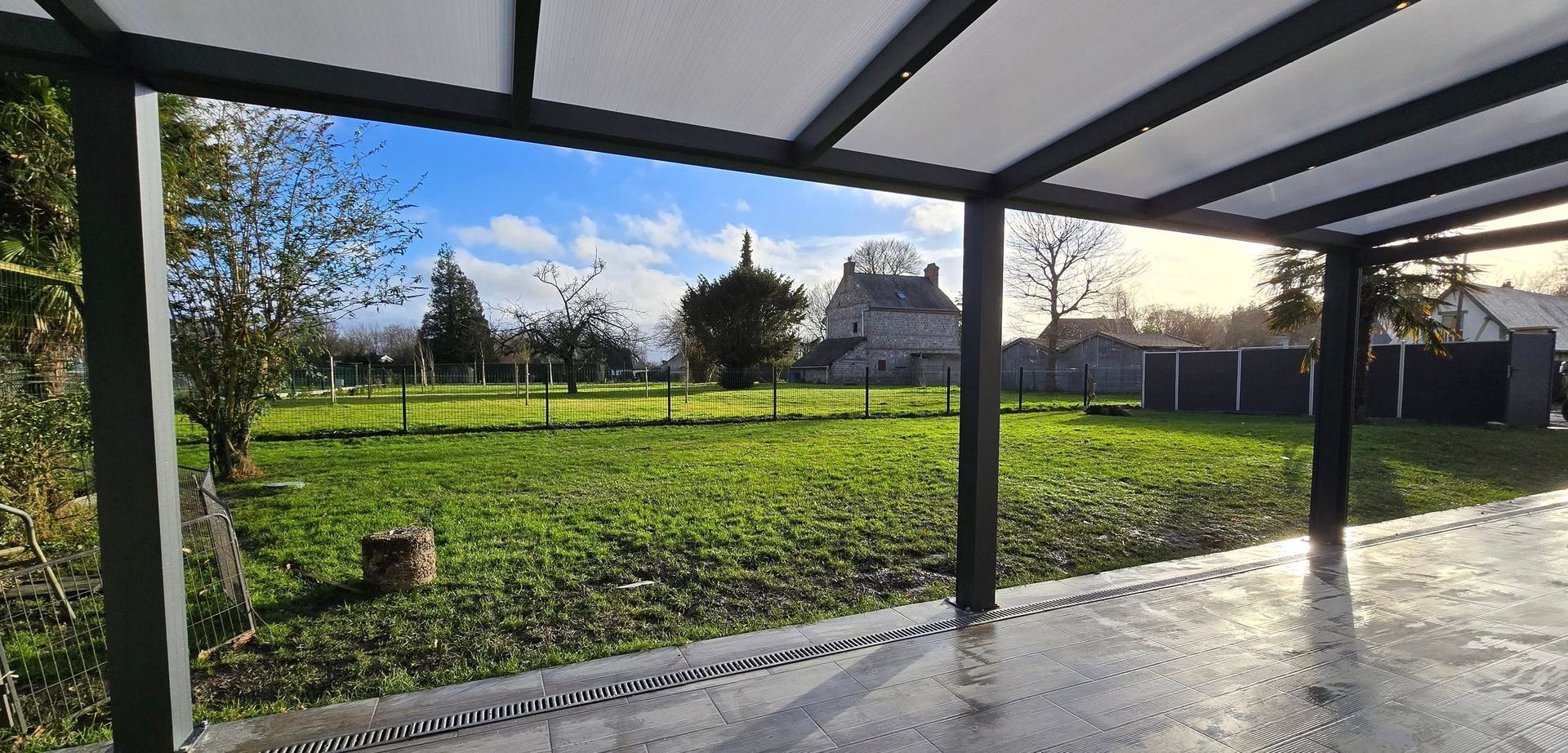 Vue du jardin depuis la terrasse sous une pergola.