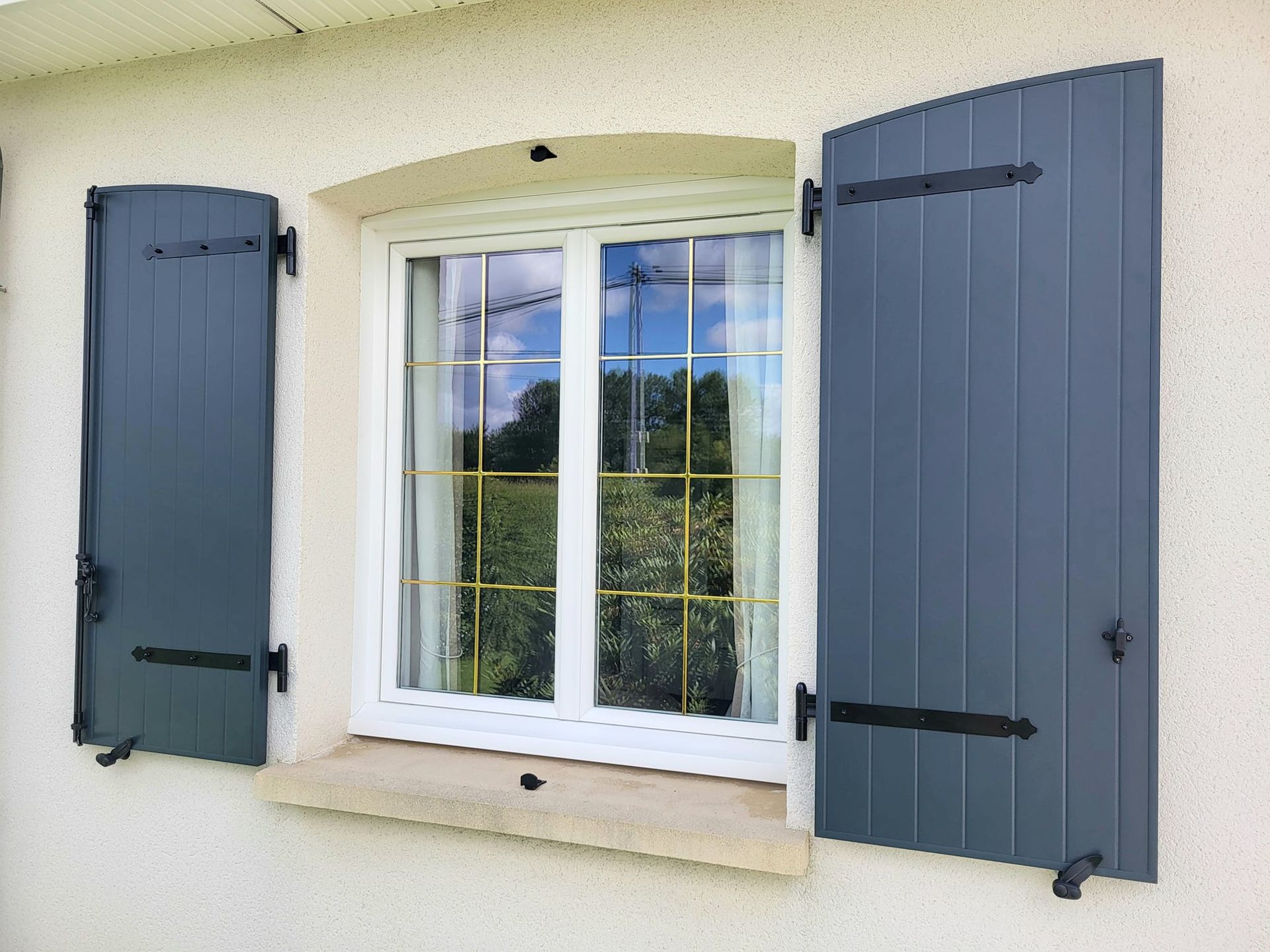 Fenêtre blanche et volets battants ouverts.