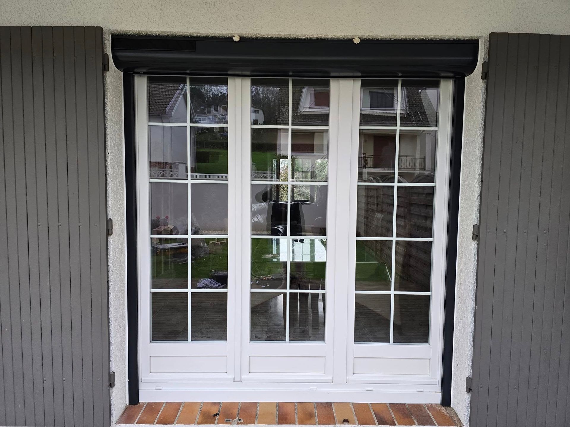 Grande porte-fenêtre blanche avec plusieurs petites vitres donnant sur l'intérieur de la maison.