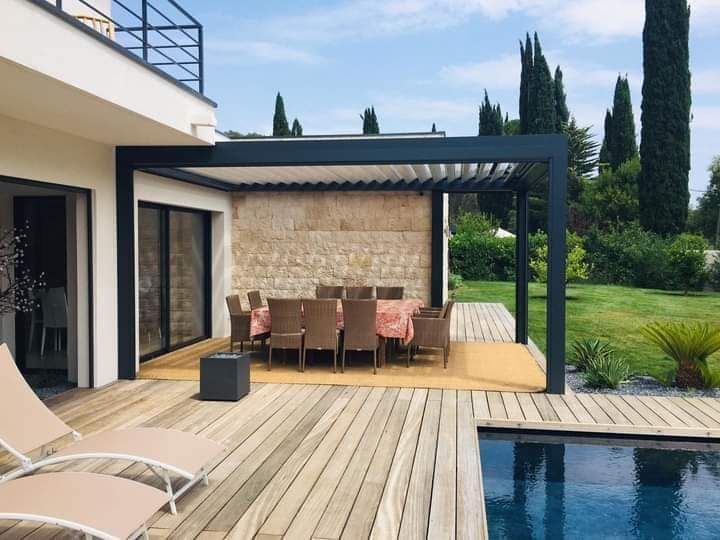 Ensemble de table et chaises sous une pergola à proximité d'une piscine.
