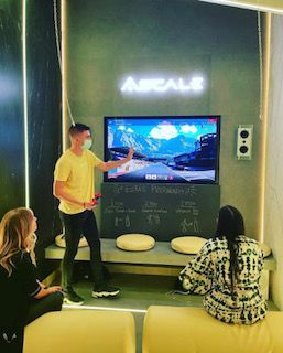 Un hombre con una camisa amarilla está parado frente a un televisor.