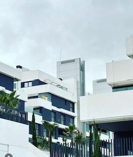 Un gran edificio blanco y azul con una valla delante.