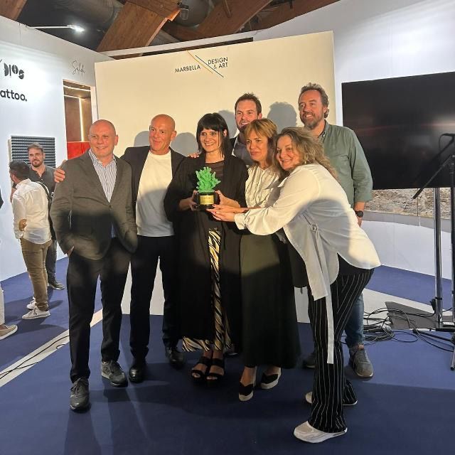 Un grupo de personas posando para una foto con una mujer sosteniendo una planta.