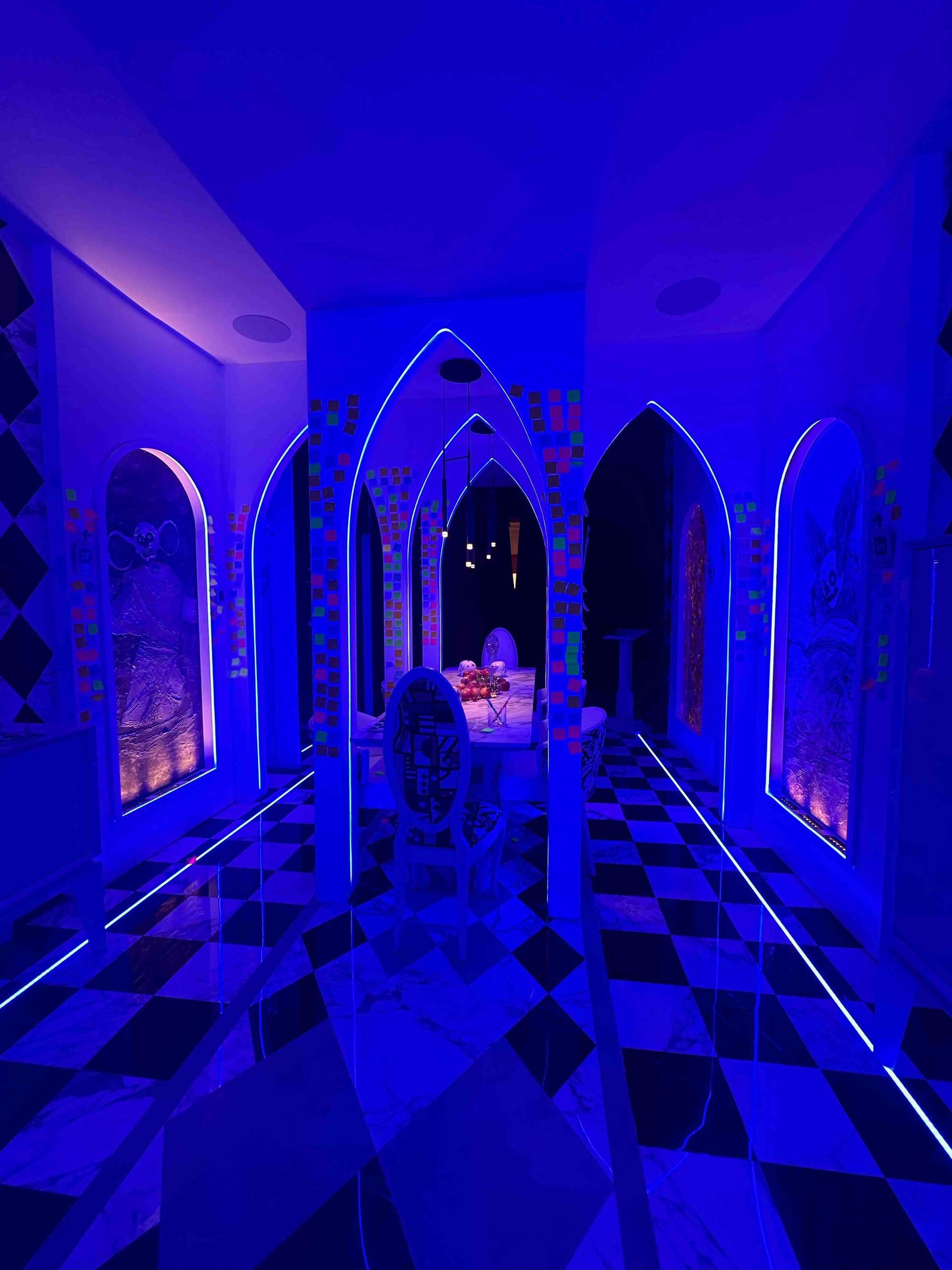 Un pasillo con luces azules y suelo cuadriculado.