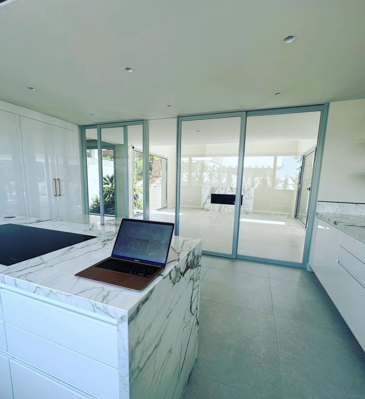 Hay una computadora portátil sobre una encimera de mármol en una cocina.