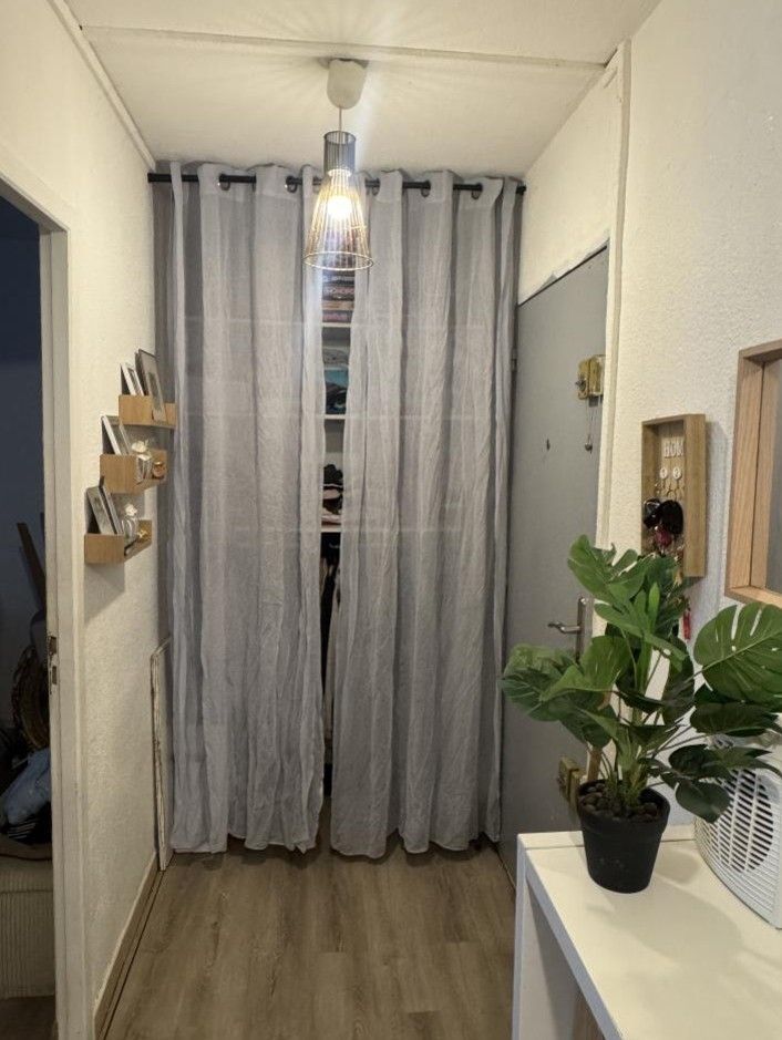 Entrée d'un appartement, avec étagères de rangement cachées par des rideaux gris
