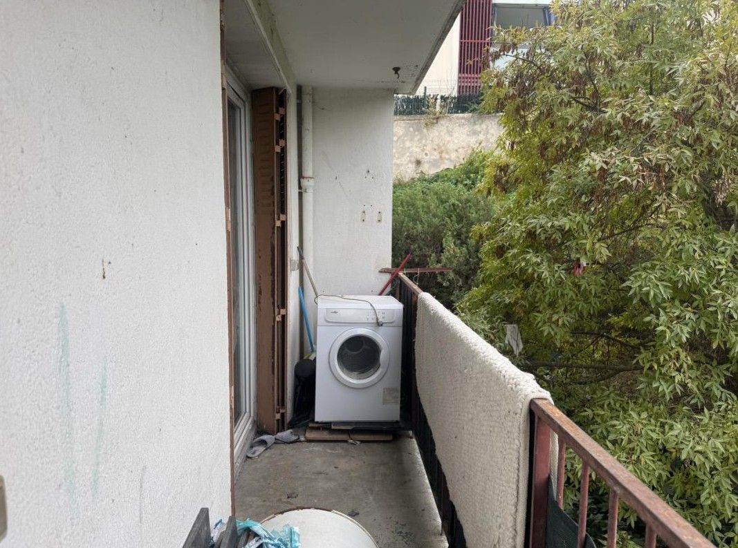 Balcon étroit d'appartement avec une machine à laver contre le mur