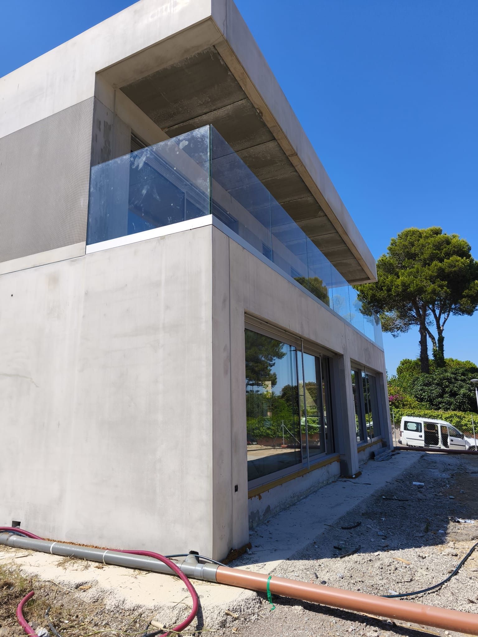 Edificio moderno de hormigón con balcón y ventanas de cristal; vista exterior.