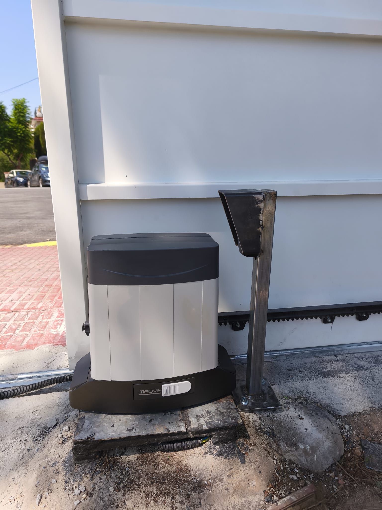 Motor para puerta corredera automática junto a puerta blanca.