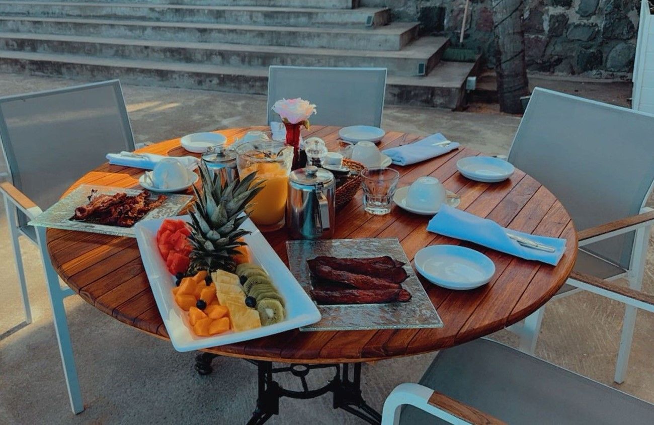 Een houten tafel met daarop borden met eten en fruit.