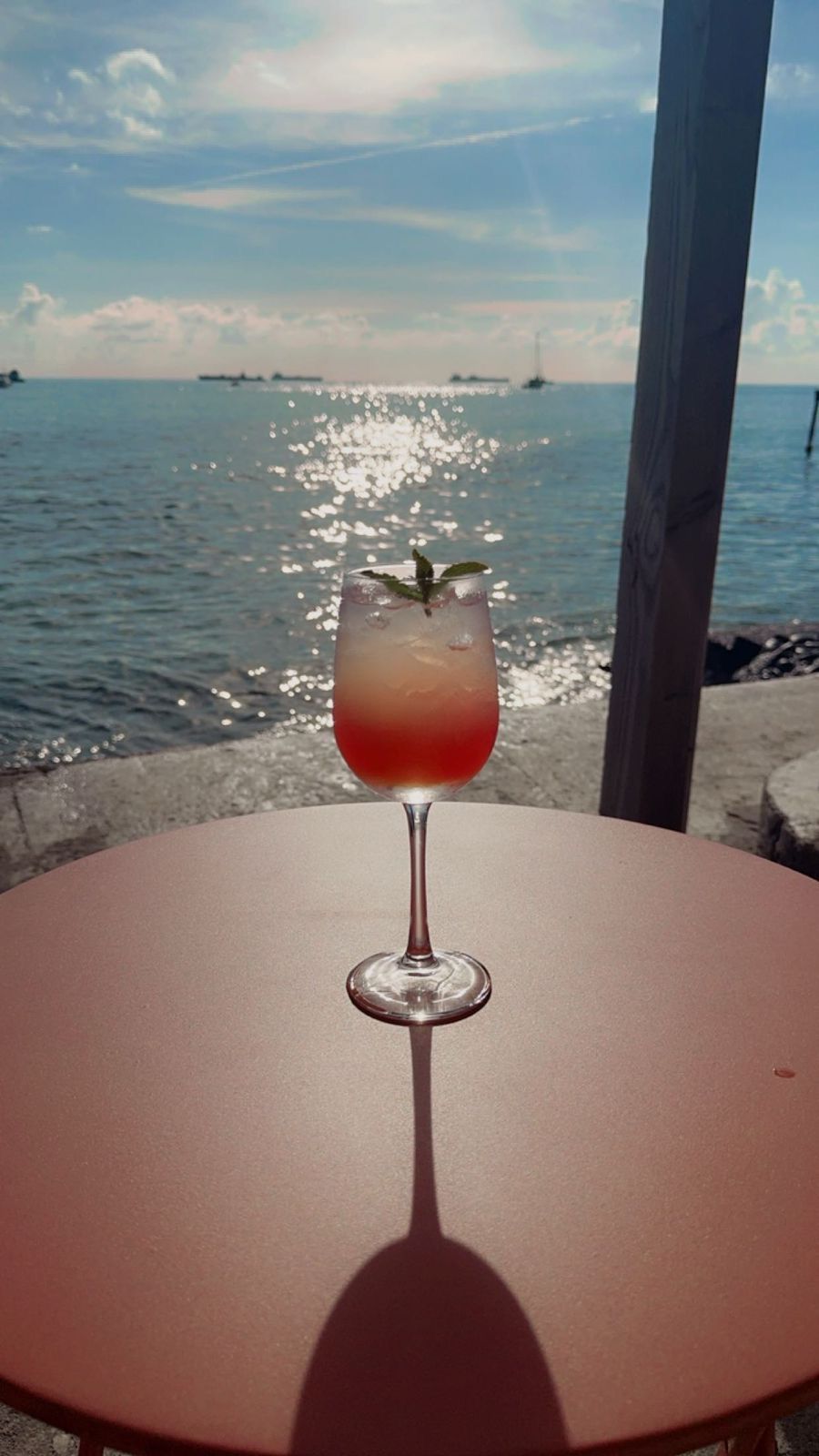 Een glas wijn staat op een tafel met uitzicht op de oceaan.