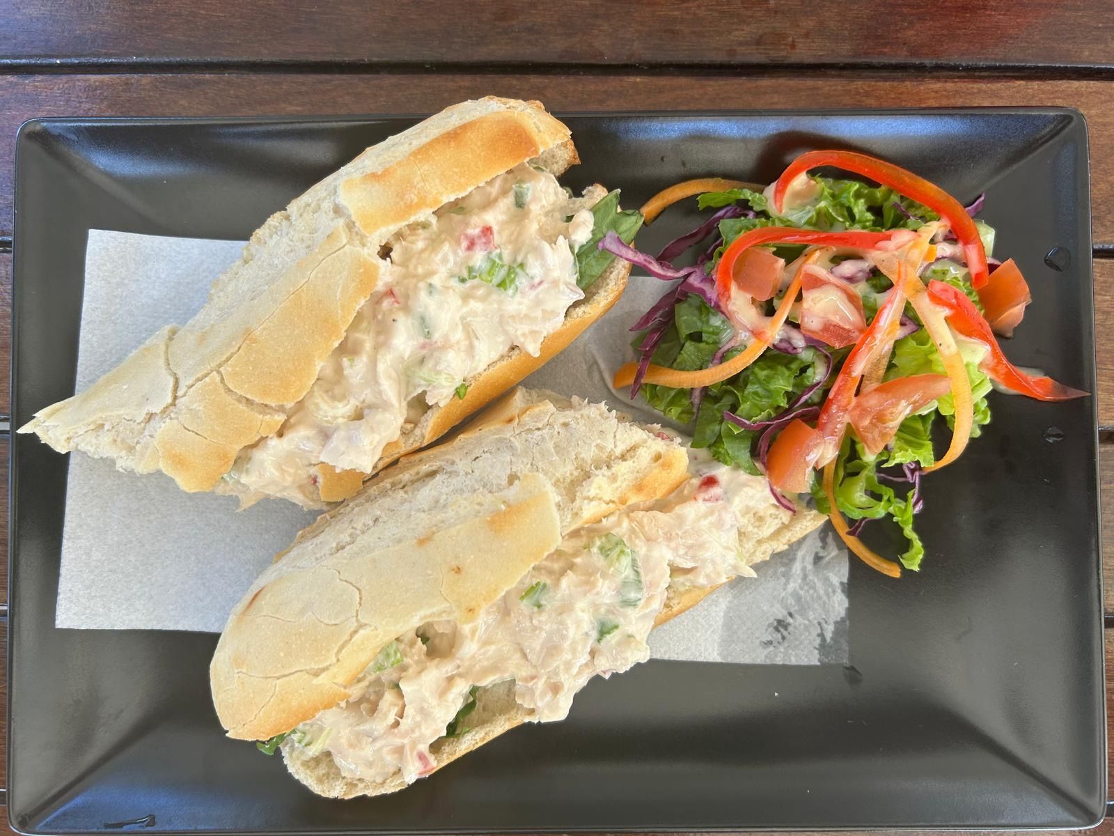 Twee sandwiches en een salade op een zwart bord