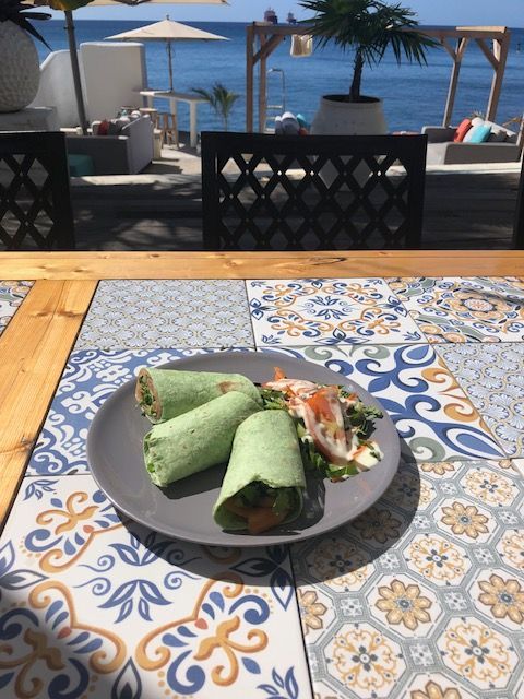 Een bord met eten op een tafel met de oceaan op de achtergrond